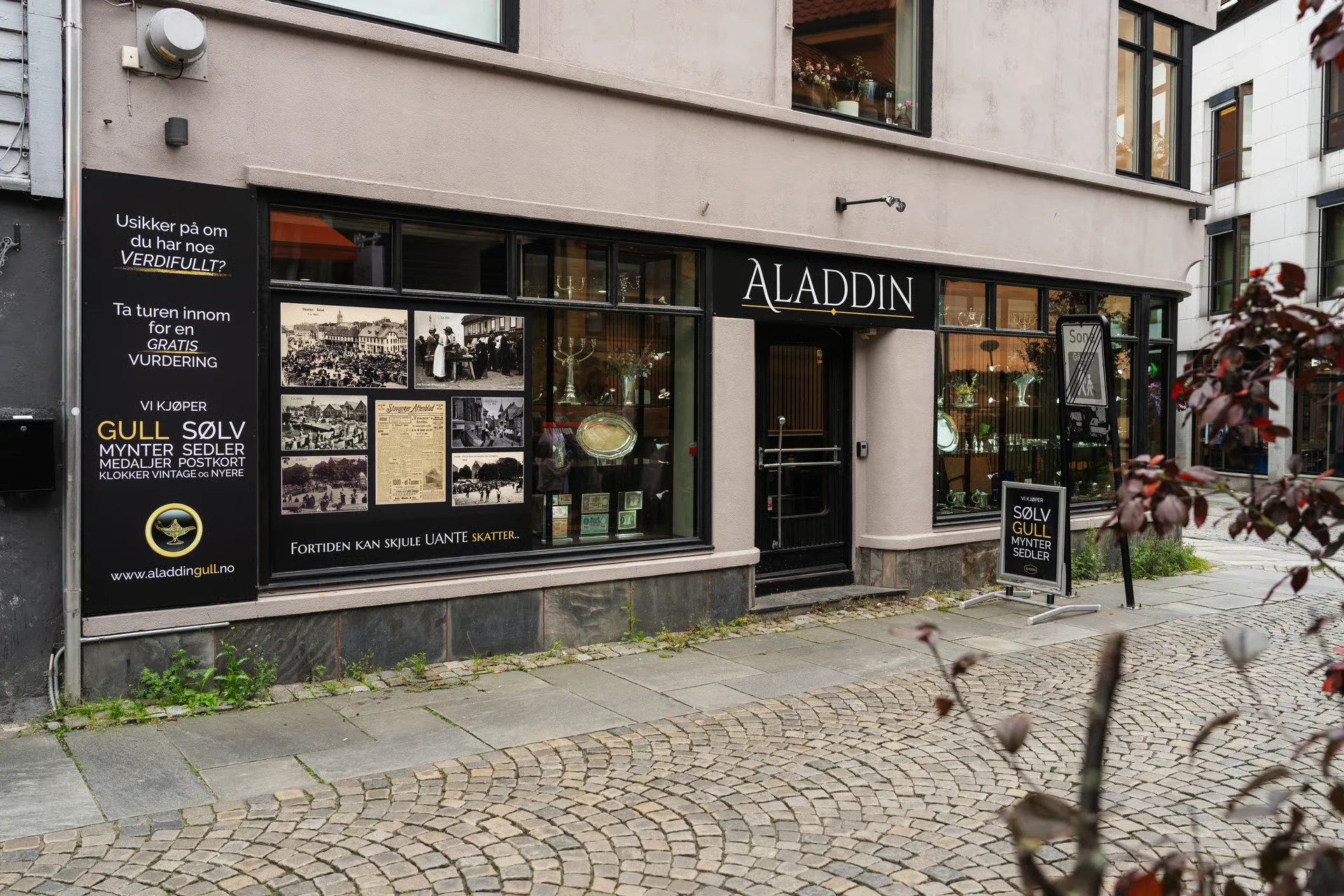 An exterior view of Aladdin, a store that buys gold, silver, and vintage items, with signs in Norwegian.