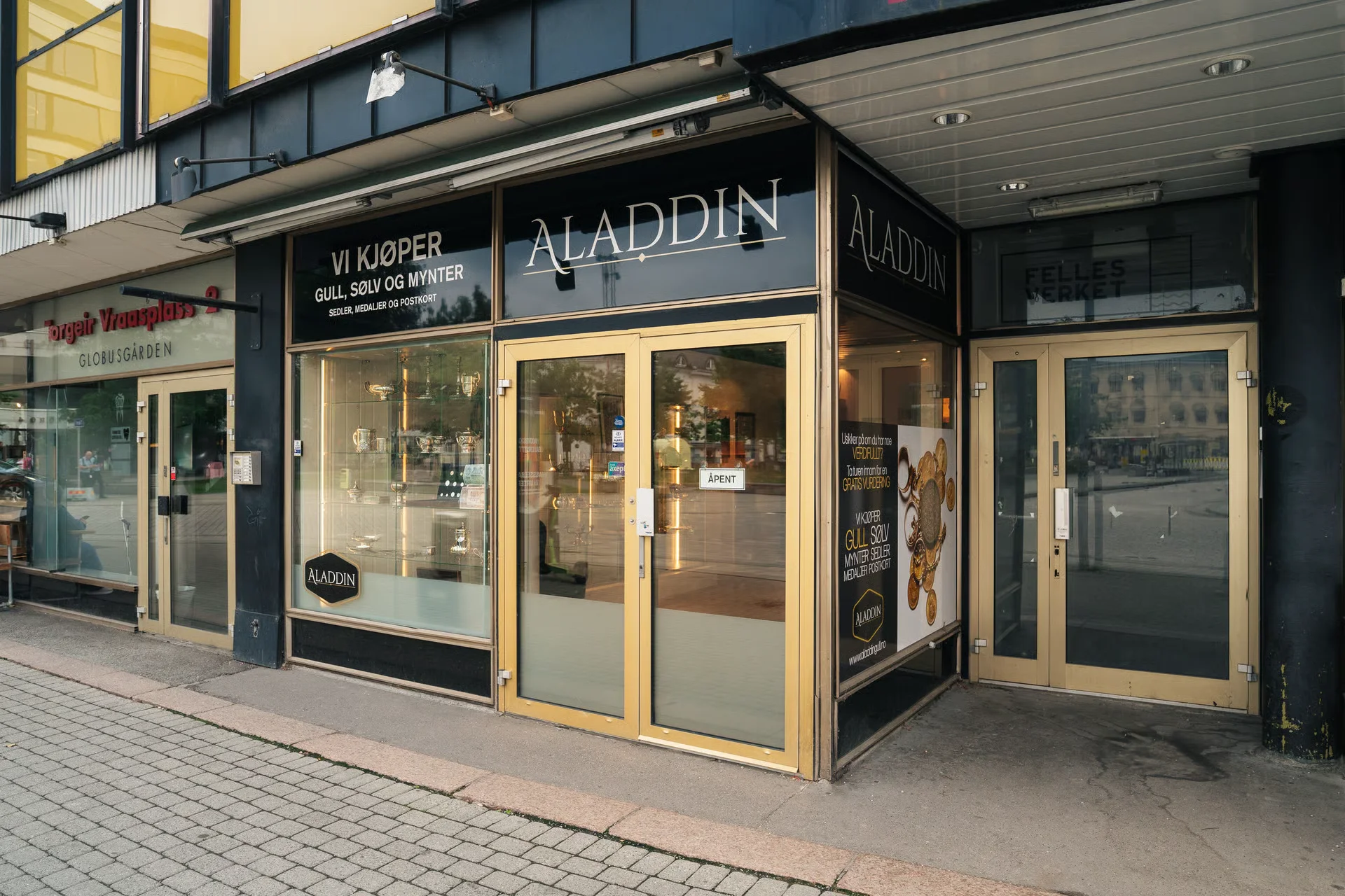 Storefront of Aladdin, a shop buying gold, silver, and coins, with adjacent businesses visible.