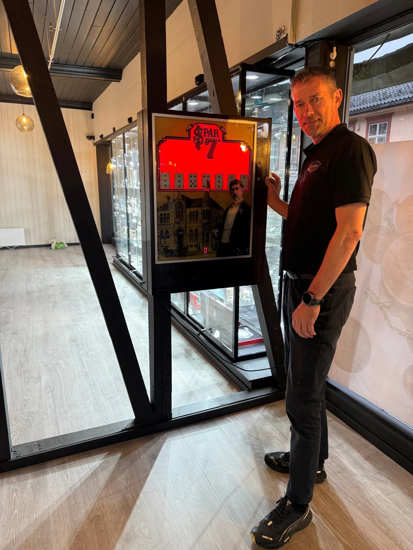 Man smiles next to a vintage 'PAR 7' arcade game machine in a store.